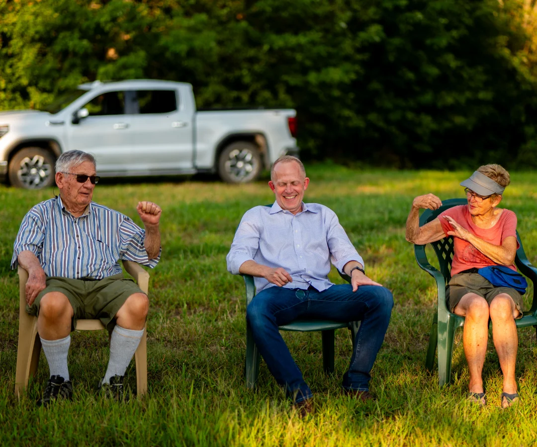 Three community members talking together outdoors in a rural field